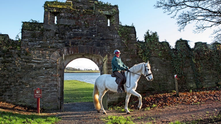 A horse and rider coming through a stone archway at Castle Ward.
